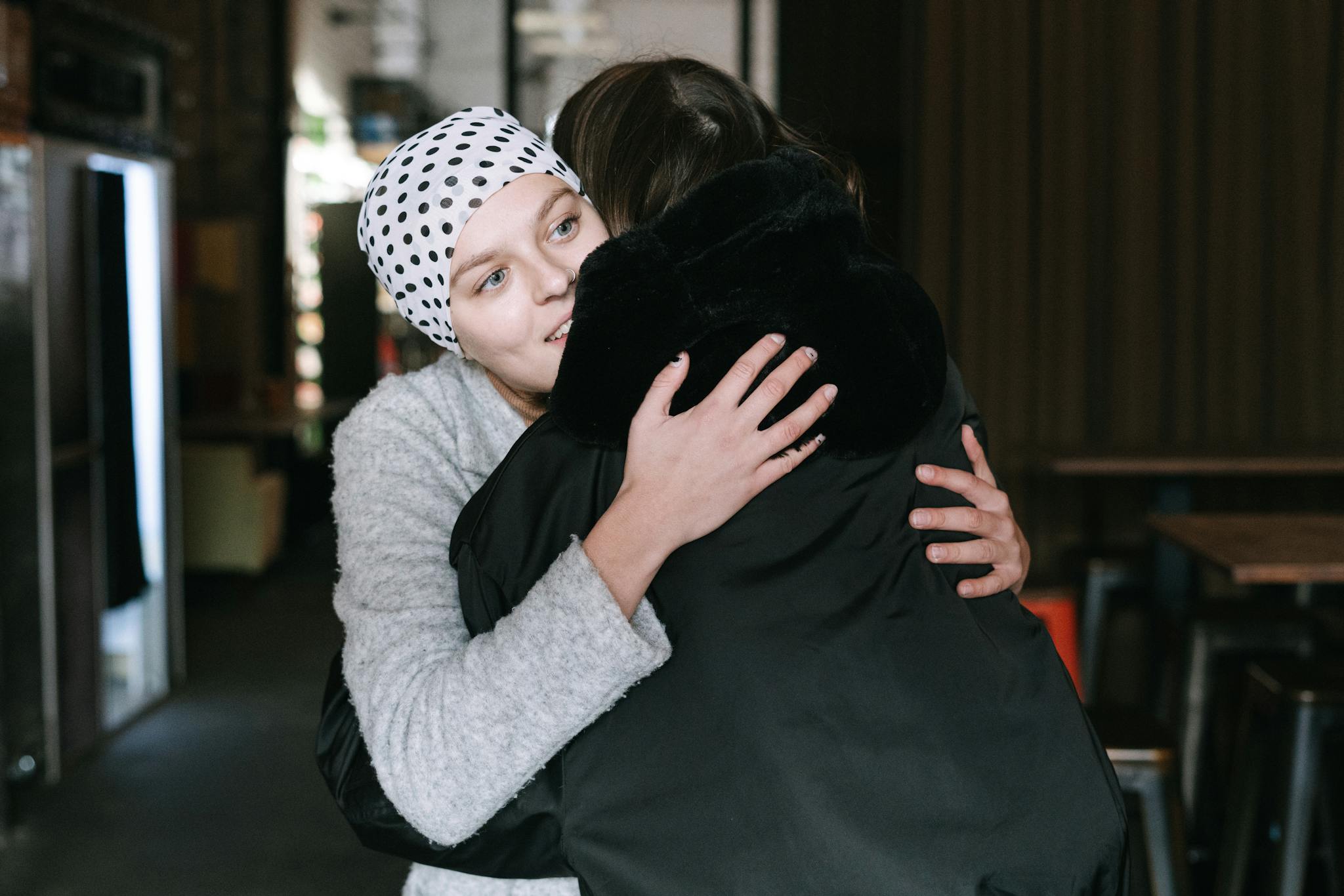 Two women hugging, showcasing support and compassion in cancer awareness indoors.